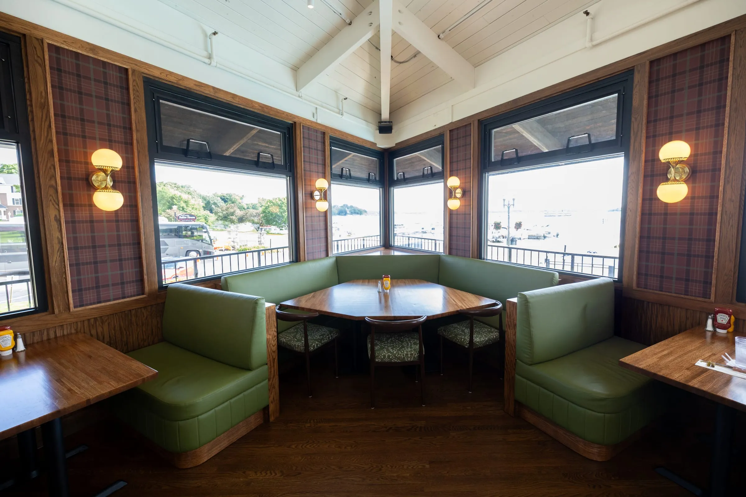 A green corner booth around a large group table at Emmi’s, wrapped in windows overlooking Lake Geneva.